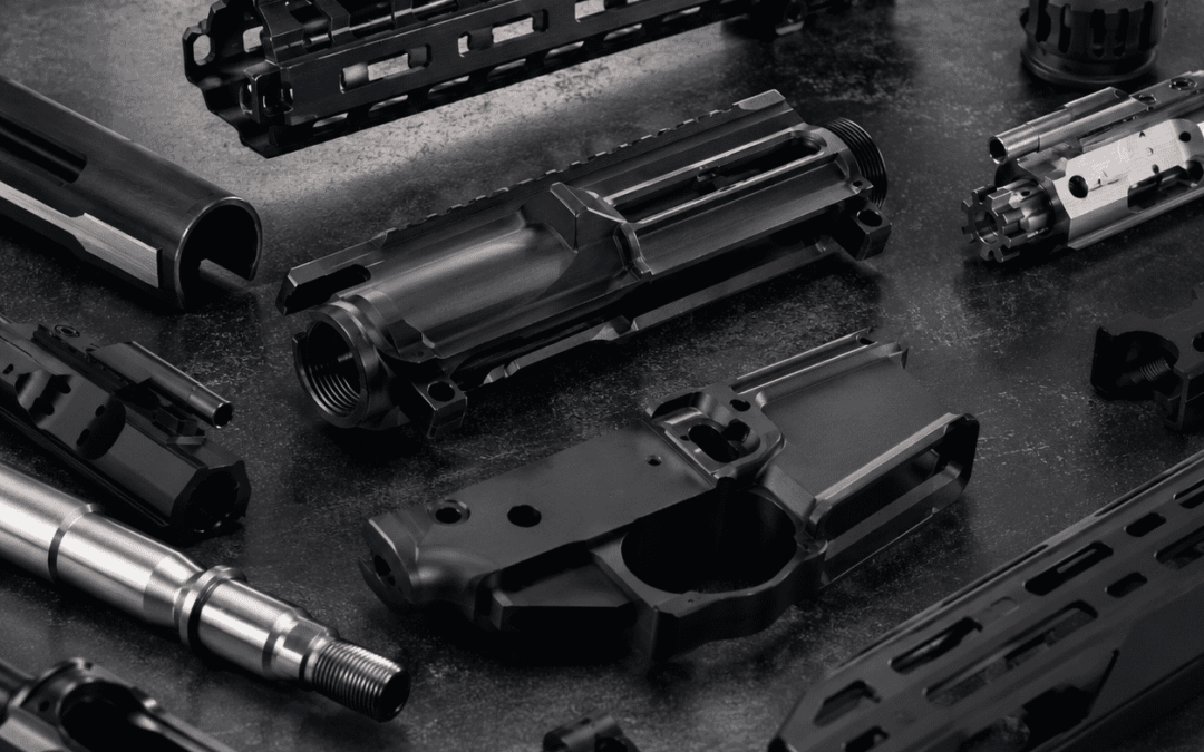 CNC Machined Gun Parts arranged on a dark industrial surface, showcasing detailed metal milling, anodized finishes, and high-performance engineering in a professional studio setting.