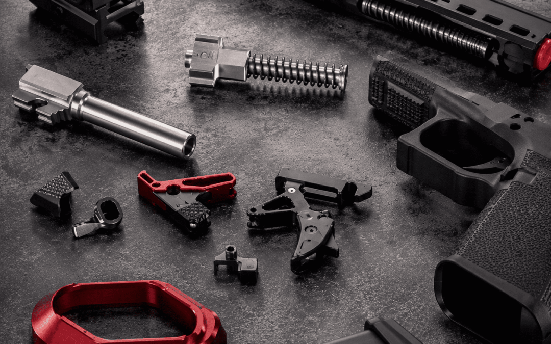 competition gun upgrades components displayed on a dark industrial surface, featuring precision-machined parts, optic accessories, trigger upgrades, and custom performance enhancements.