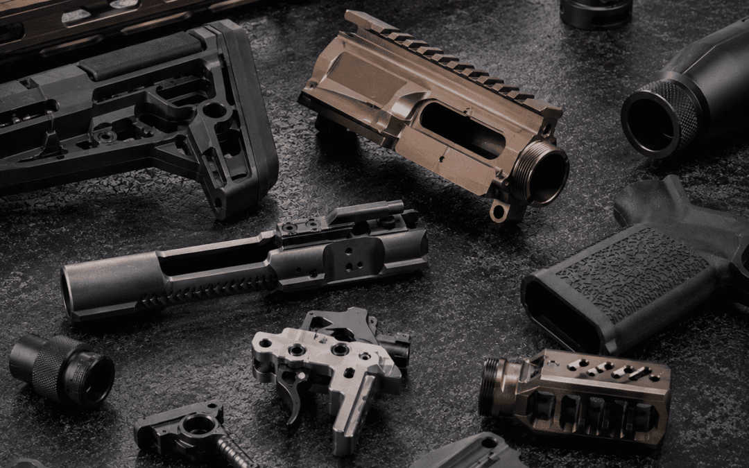 Custom firearm parts and precision-machined components displayed on a dark industrial surface, featuring upgraded receivers, triggers, grips, and performance accessories with premium metal finishes.