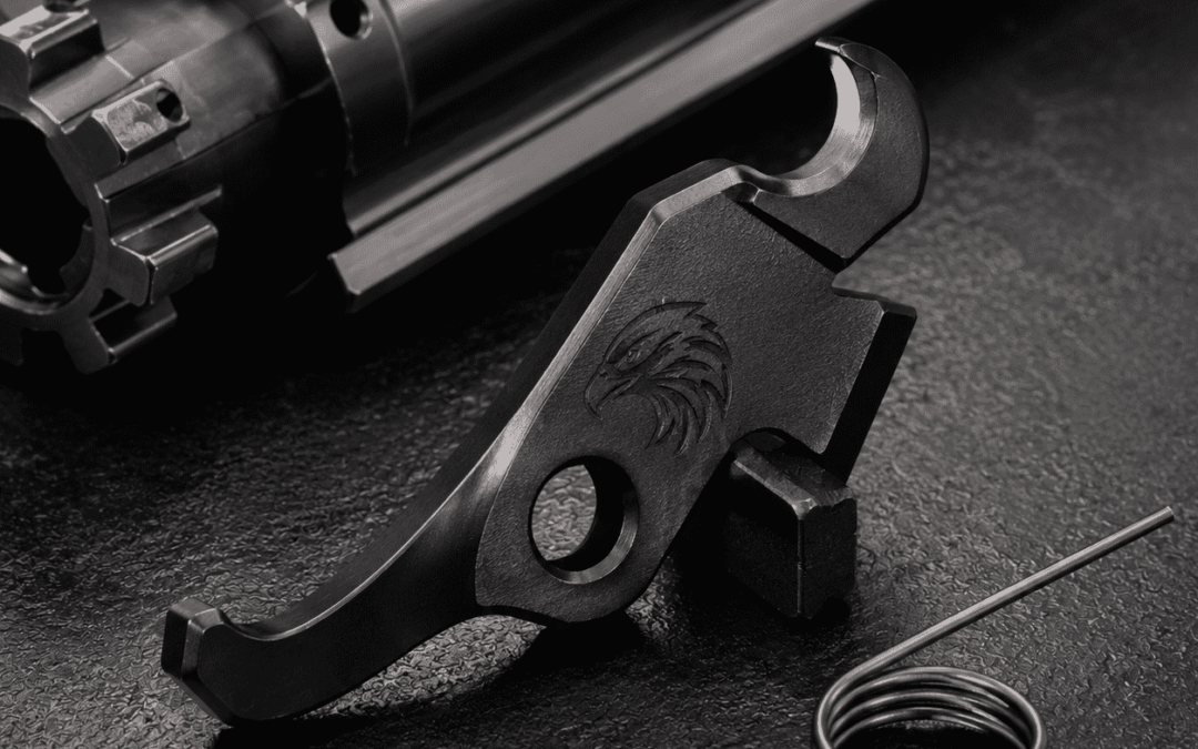 Eagle's Talon extractor component displayed beside a spring and bolt assembly on a dark textured surface, highlighting detailed craftsmanship and premium metal construction.